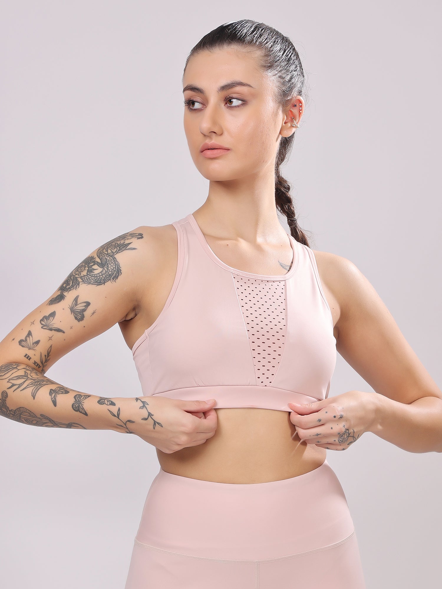 Woman wearing a pink sports bra and leggings against a plain background