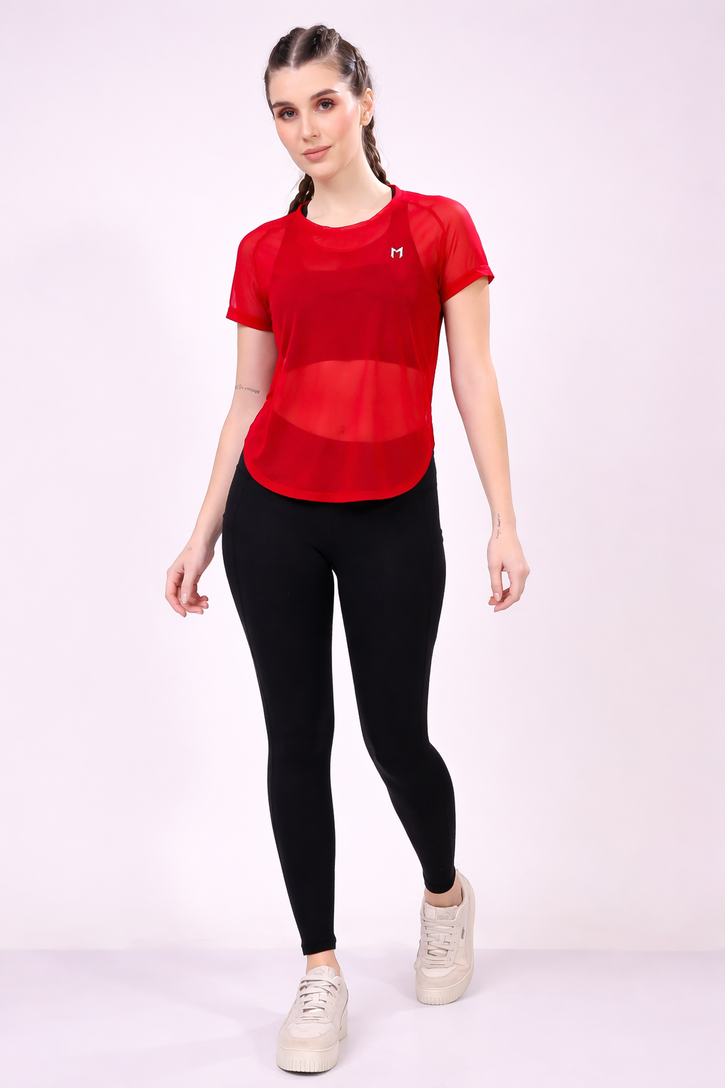 Woman wearing a red athletic shirt and black leggings on a white background
