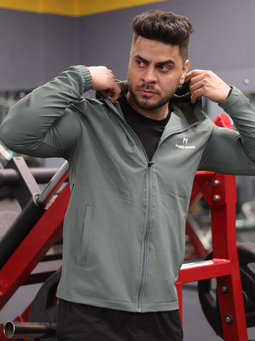 Man adjusting a gray jacket in a gym setting