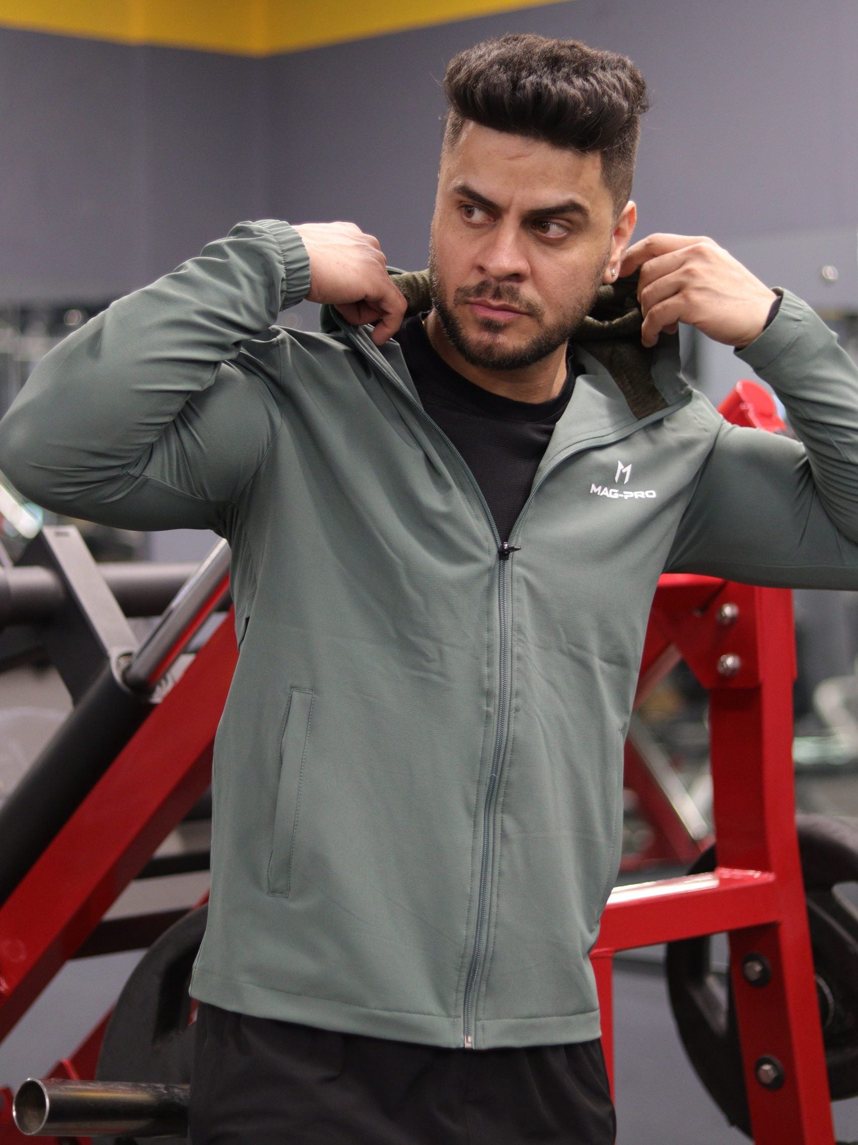 Man adjusting a gray jacket in a gym setting